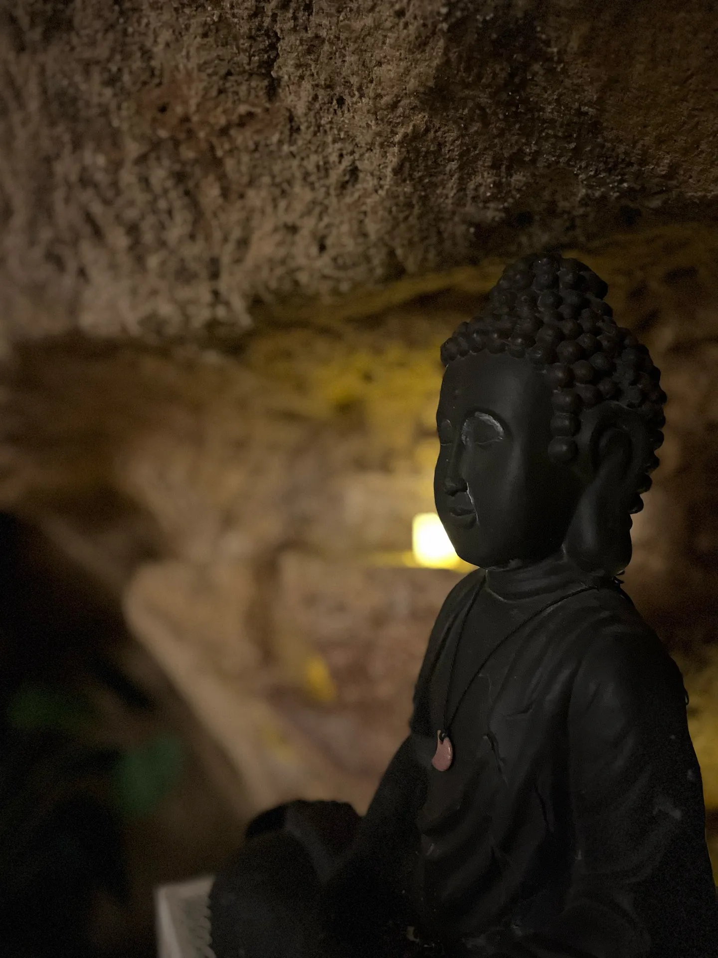 figura de buda junto a la pared de piedra, a media luz
