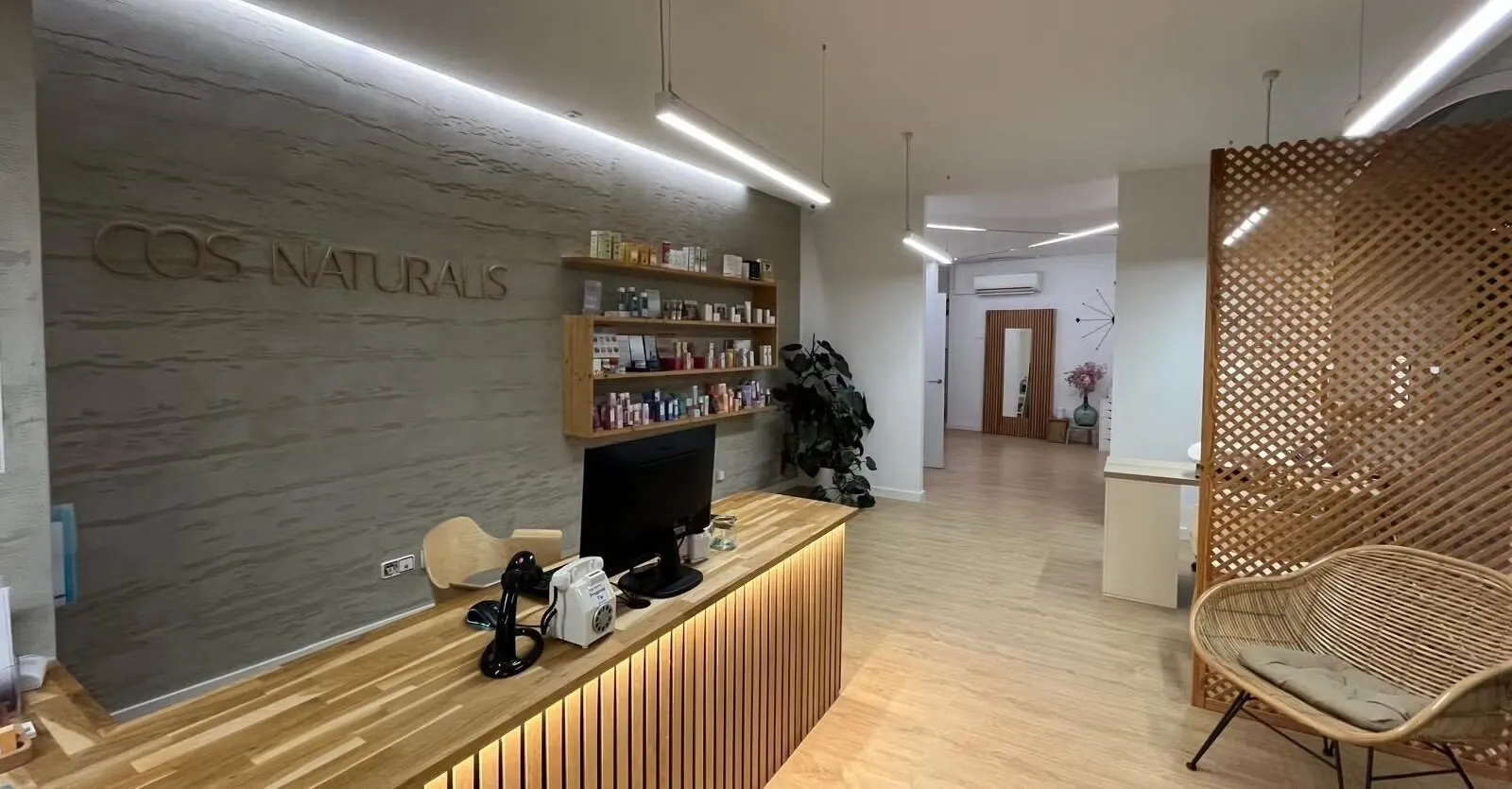 recepción de cos naturalis, mostrador de madera iluminado y rótulo sobre pared de piedra