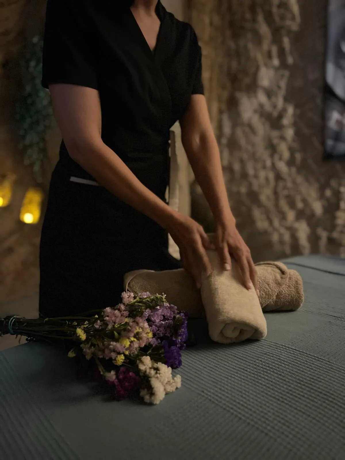 toallas y flores secas en la sala de masajes, a la luz de las velas